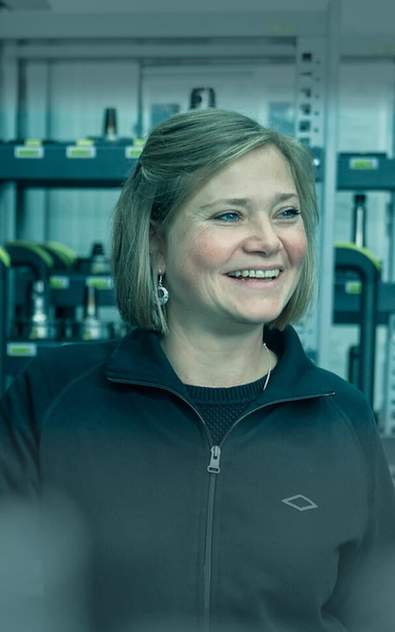 Eine Mitarbeiterin von GEDIA befindet sich an ihrem Arbeitsplatz und lacht.